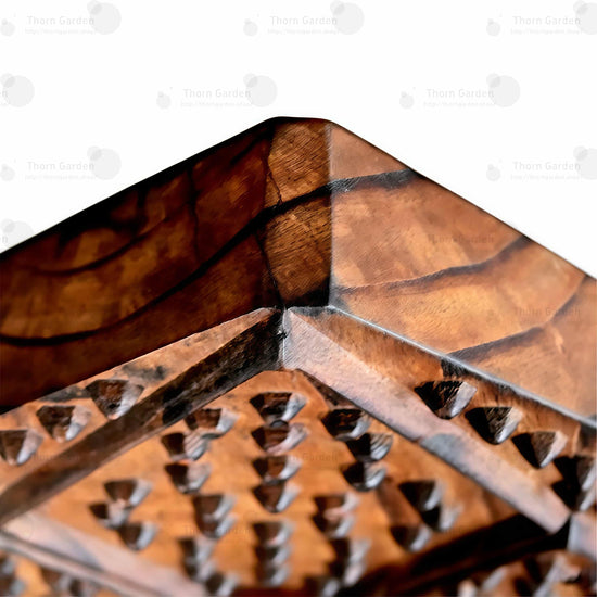 Close-up of high pointed wooden backrest with round neck opening, studded spiked texture, and metal chains