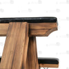 Close-up of padded black leather seat tops with side-mounted metal O-rings and rivet details on wooden bondage bench