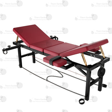 High-angle overview of the THORN GARDEN Adjustable BDSM Bondage Bed - TGZDCPLUS featuring professional-grade black steel frame, burgundy leather padded sections, gold-colored mechanical support rods, and chain restraints