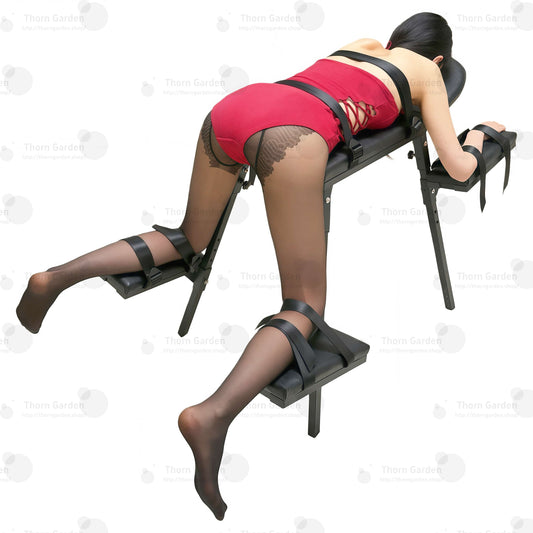 Takaoikealta yläviistosta kuvattu malli punaisessa bodyssa ja korkokengissä THORN GARDEN Professional Adjustable Spanking Bench TG025 -piiskauspenkkiin kiinnitettynä. Kuvassa korostuvat ergonominen monityynyjärjestelmä ja tukeva runko.
