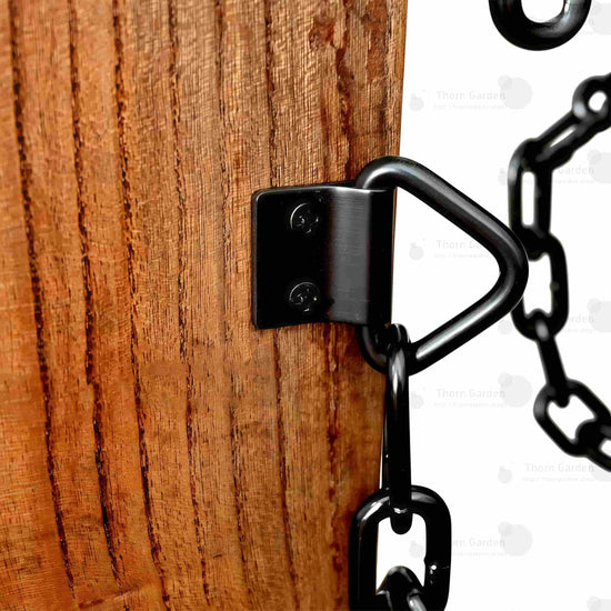 Detail van handgesneden houten armleuningen met zwarte metalen kettingen en leren polsboeien