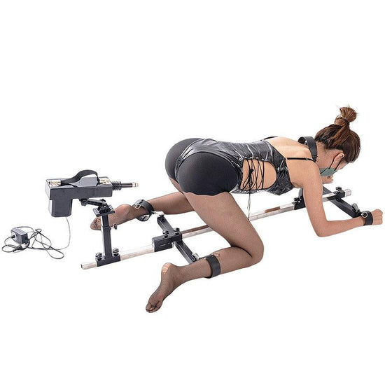 Studio product model full angle view of the THORN GARDEN 3G Bondage Stockade with metalcuffs showcasing a model secured in a four-limb restraint rack with an electric sex machine against a clean background