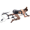 Studio product model rear angle view of the THORN GARDEN 3G Bondage Stockade with metalcuffs showcasing a model secured in a four-limb restraint rack with an electric sex machine against a clean background